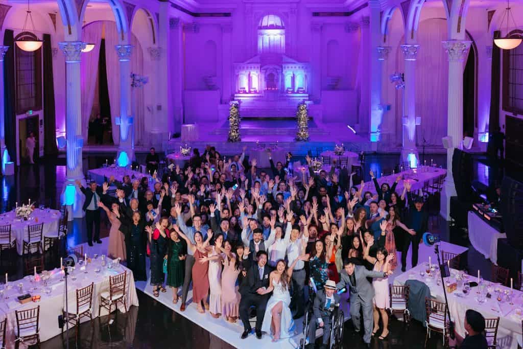 Packed floor under purple uplighting, wide, Charisse & Fred wedding at Vibiana